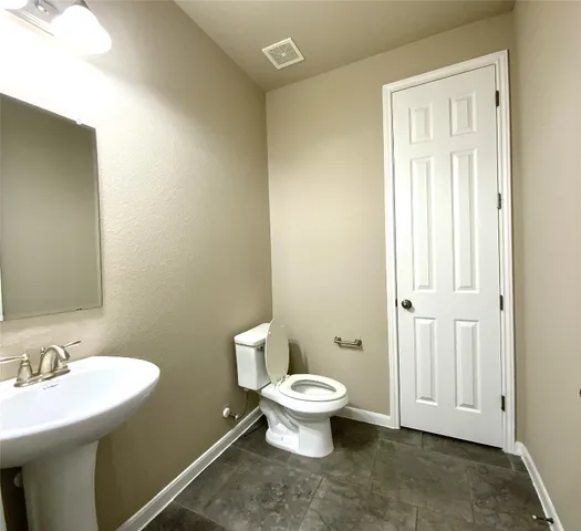 a bathroom with a toilet a sink a mirror and vanity