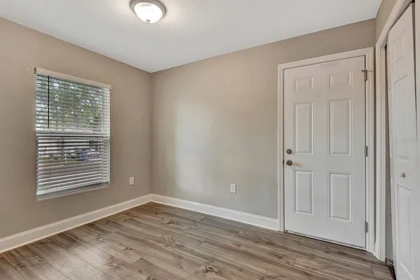 a view of an empty room with wooden floor and a window