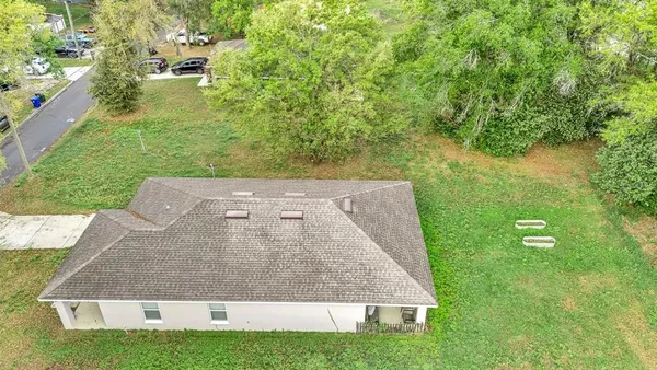 an aerial view of residential house with outdoor space and trees all around