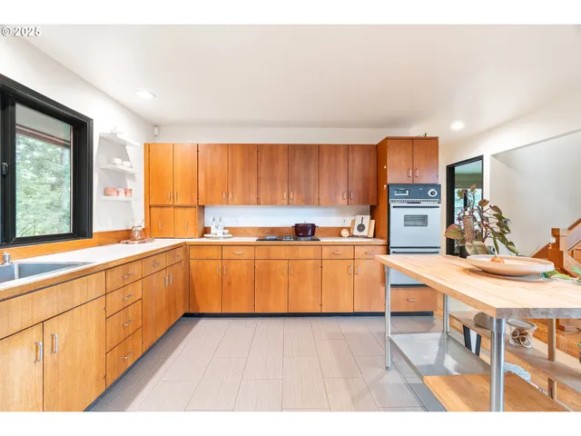 a kitchen with stainless steel appliances a refrigerator a sink dishwasher with a dining table and chairs