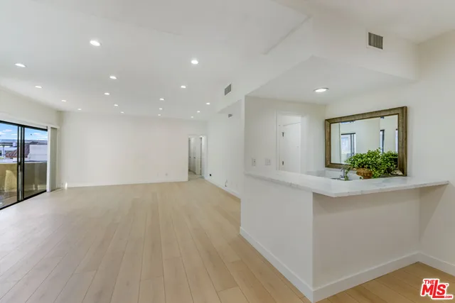 a view of an empty room with kitchen and a window