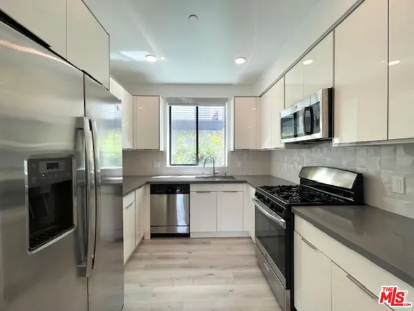 a kitchen with stainless steel appliances granite countertop a stove a sink and a refrigerator