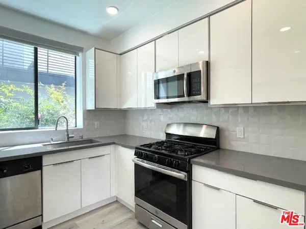 a kitchen with stainless steel appliances granite countertop white cabinets granite counter tops and a window