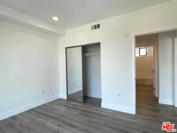 a view of an empty room with wooden floor & closet