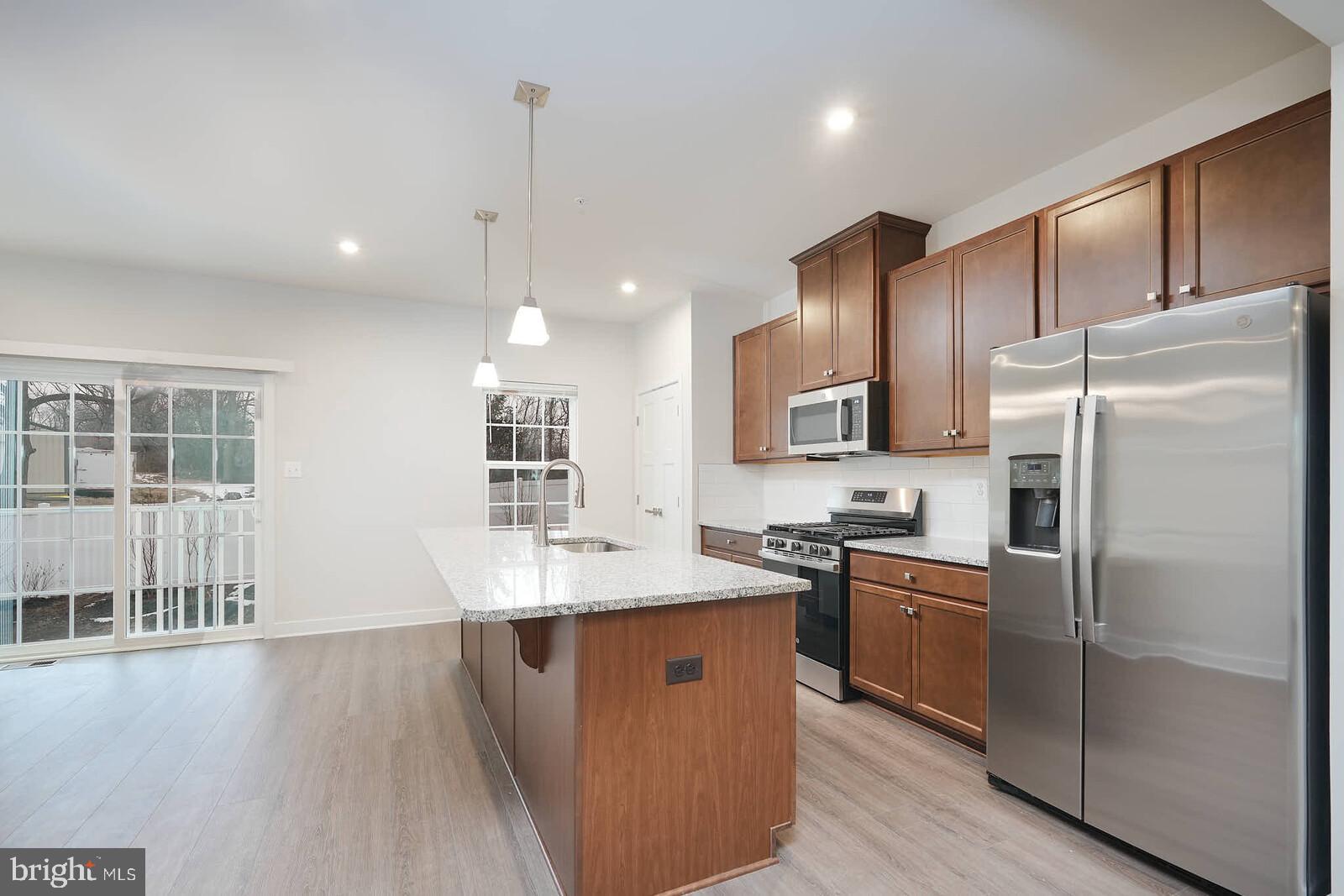 336 Paca Gardens Lane Frederick, MD 21703 - Photo 15 of 36 a kitchen with stainless steel appliances granite countertop a sink a stove a refrigerator and island with wooden floor
