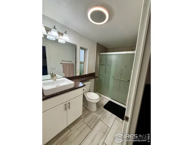 a bathroom with a granite countertop toilet sink and mirror
