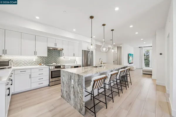 a kitchen with granite countertop a table chairs stove and white cabinets