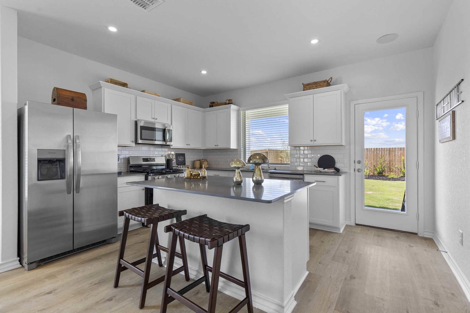 105 Hatari Trail Jarrell, TX 76537 - Photo 2 of 27 White cabinetry paired with a central prep island anchors this modern, light-filled kitchen space.