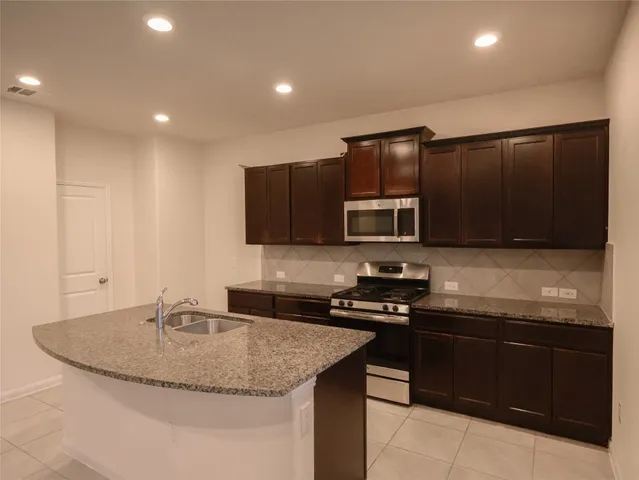 a kitchen with stainless steel appliances granite countertop a sink and a stove