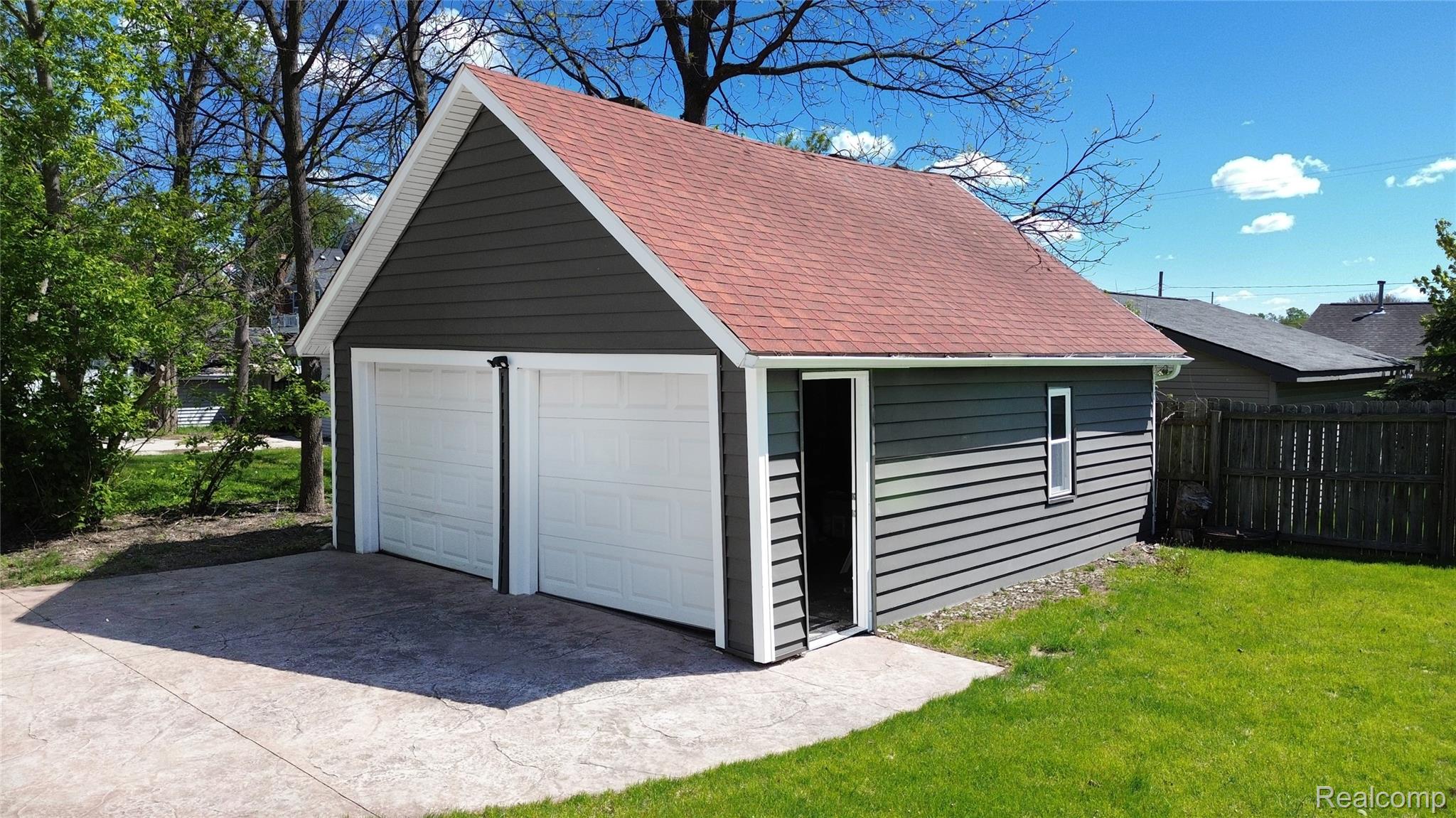 404 North Adelaide Street Fenton, MI 48430 - Photo 22 of 23 Detached two-car garage with white paneled doors, gray horizontal siding, and a red shingle roof