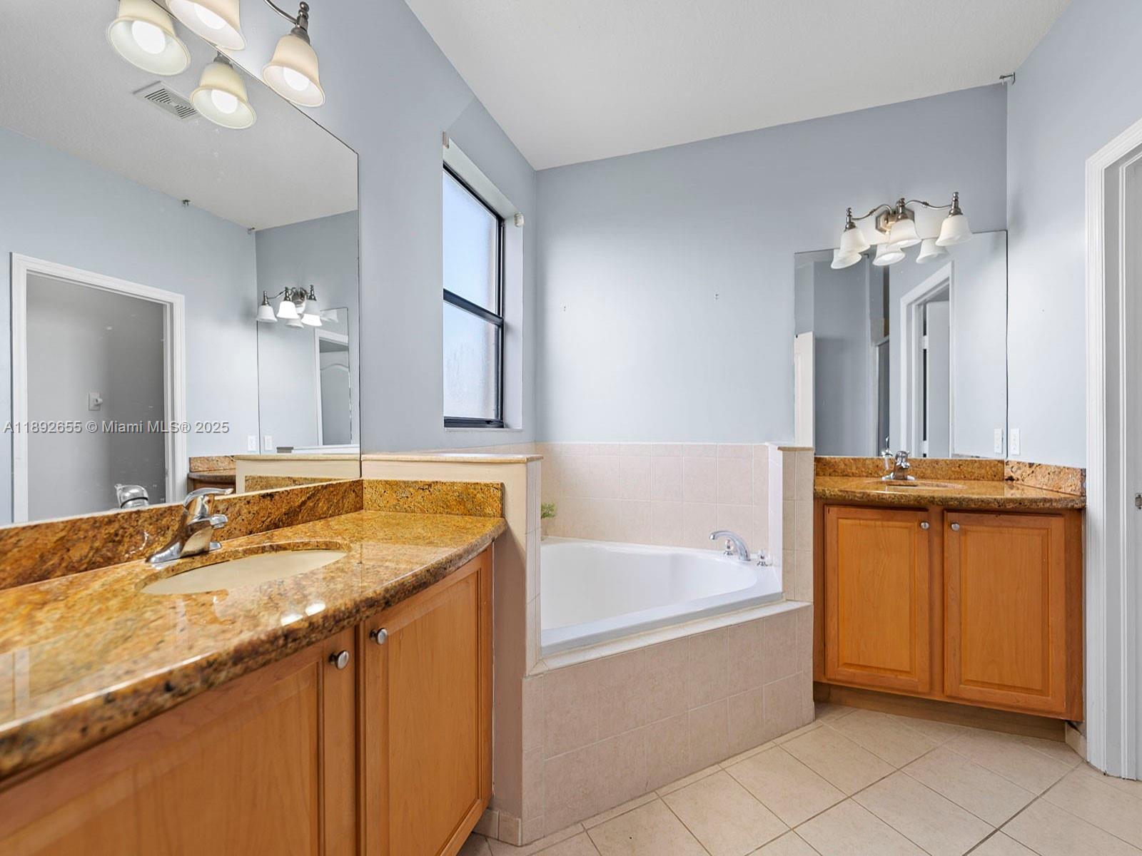 11279 Southwest 238th Street Homestead, FL 33032 - Photo 28 of 40 a bathroom with a granite countertop sink a bathtub a mirror and a bathtub