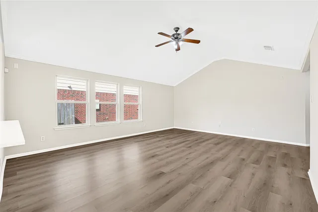 an empty room with wooden floor fan and windows
