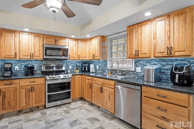 a kitchen with stainless steel appliances granite countertop a stove sink microwave and window