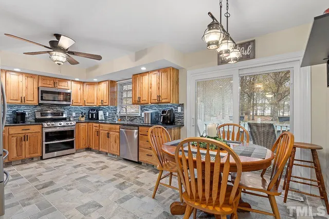 a kitchen with stainless steel appliances granite countertop a stove top oven a sink dishwasher a dining table and chairs with wooden floor