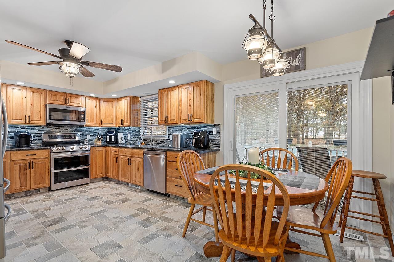 2683 C Rains Crossroads Road Selma, NC 27576 - Photo 13 of 30 a kitchen with stainless steel appliances granite countertop a stove top oven a sink dishwasher a dining table and chairs with wooden floor