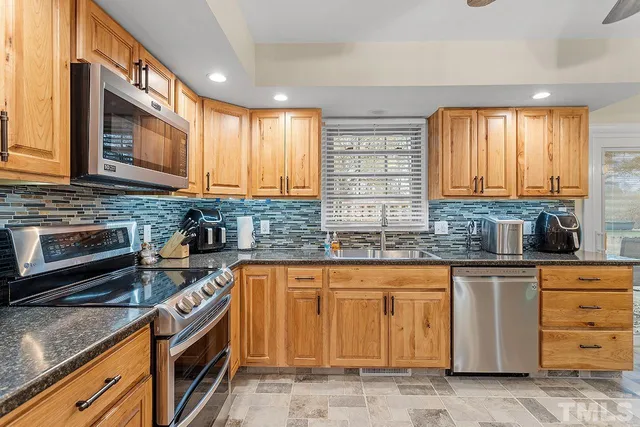 a kitchen with stainless steel appliances granite countertop a stove a sink and a microwave