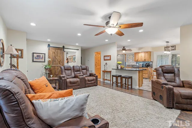 a living room with furniture kitchen view and a large window