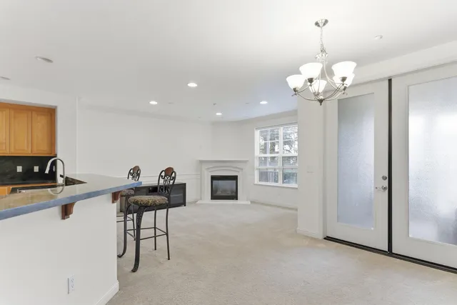a view of a livingroom with a fireplace a chandelier and windows