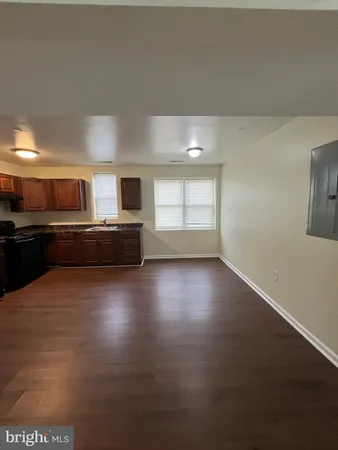 a view of a livingroom with wooden floor and kitchen