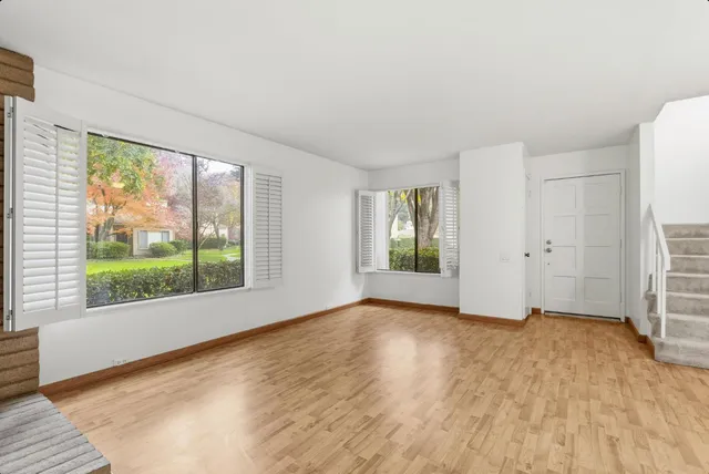 a view of an empty room with a window and wooden floor