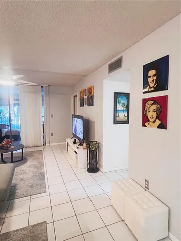a view of a refrigerator in kitchen and an empty room