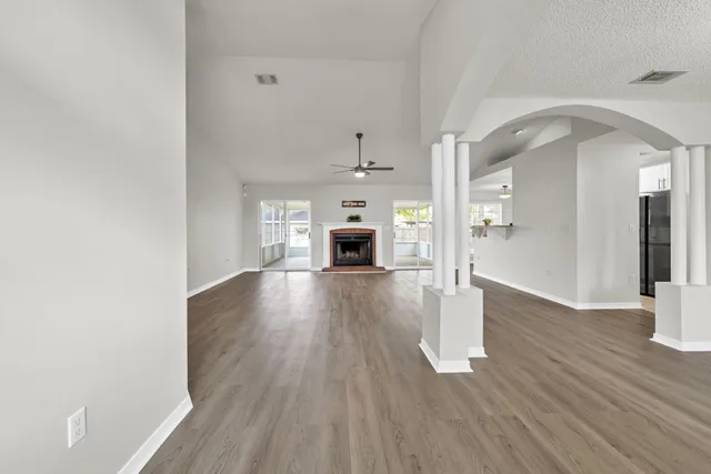 an empty room with wooden floor fireplace and windows