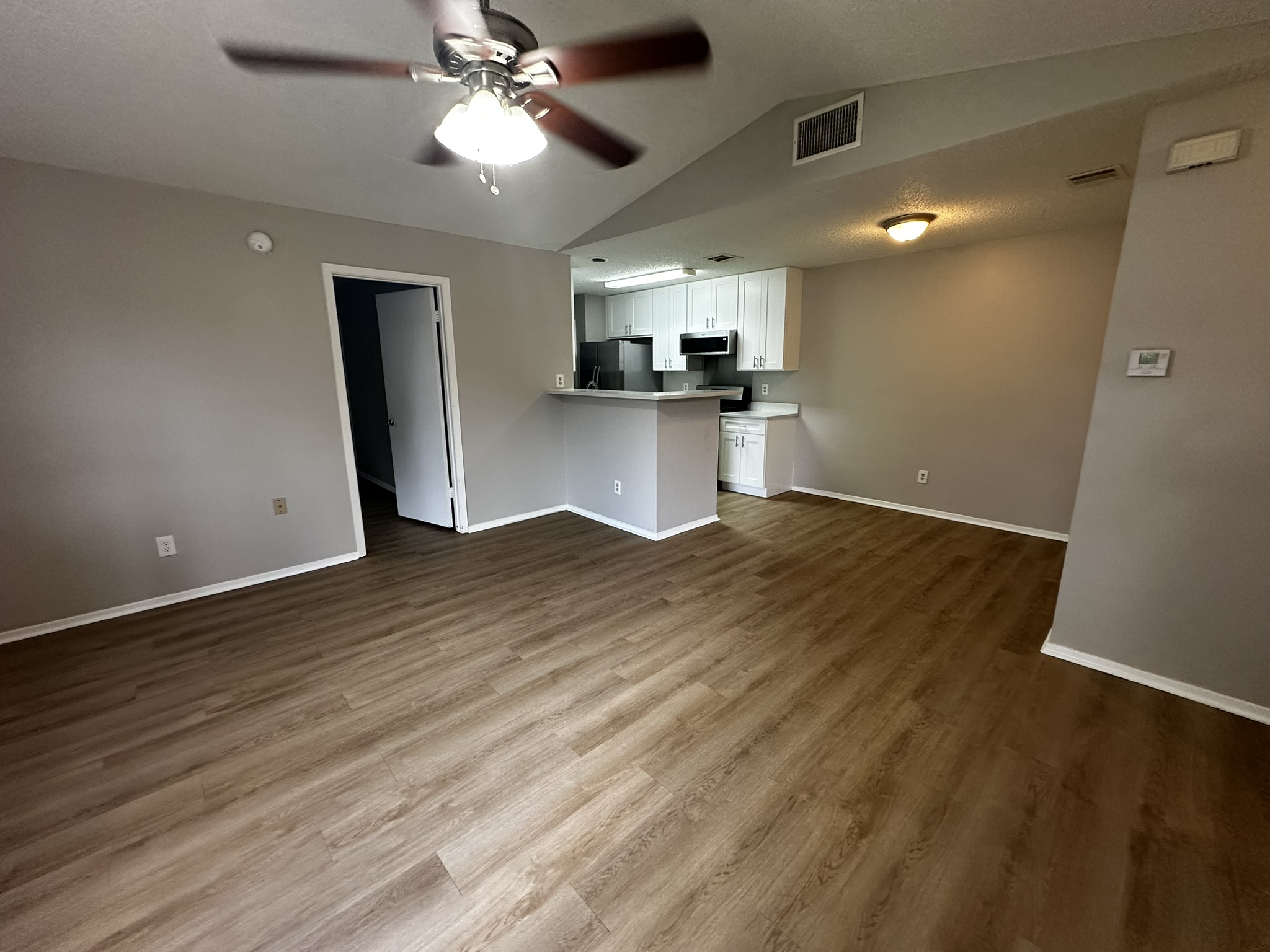 7900 West Gate Boulevard, Unit B Austin, TX 78745 - Photo 16 of 16 An open floorplan seamlessly connects the living area to a modern kitchen, featuring vaulted ceilings and hard surface flooring.
