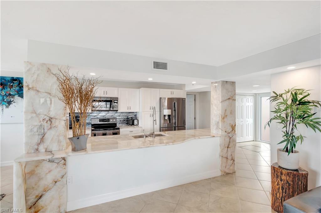 11 Bluebill Avenue, Unit 1101 Naples, FL 34108 - Photo 15 of 40 a large white kitchen with cabinets a sink a window and stainless steel appliances