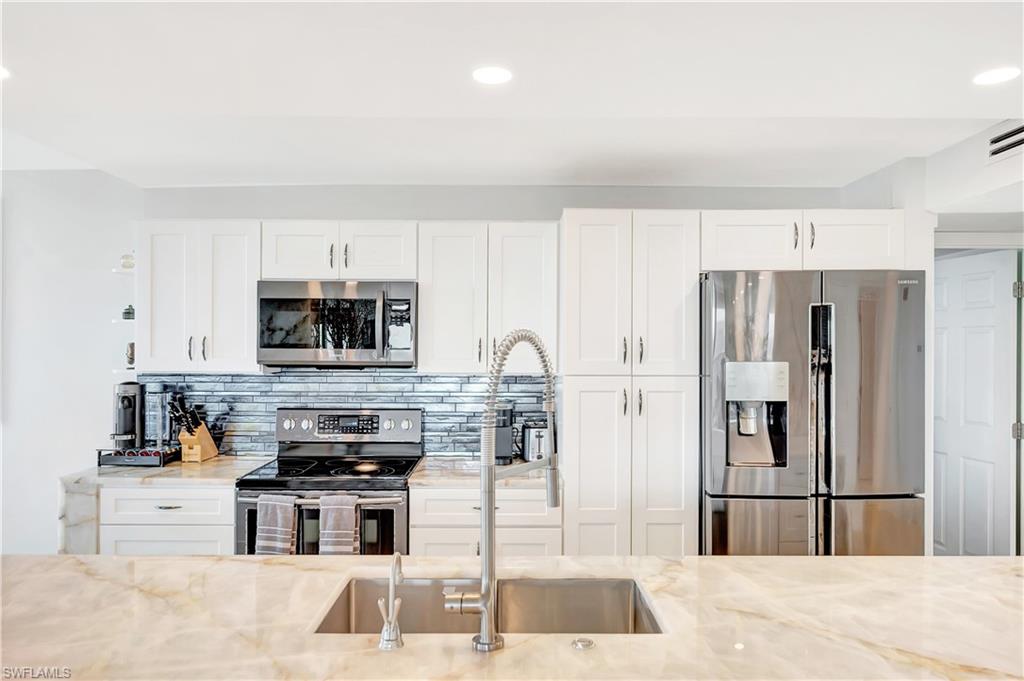11 Bluebill Avenue, Unit 1101 Naples, FL 34108 - Photo 20 of 40 a kitchen with stainless steel appliances kitchen island granite countertop a refrigerator and a stove top oven
