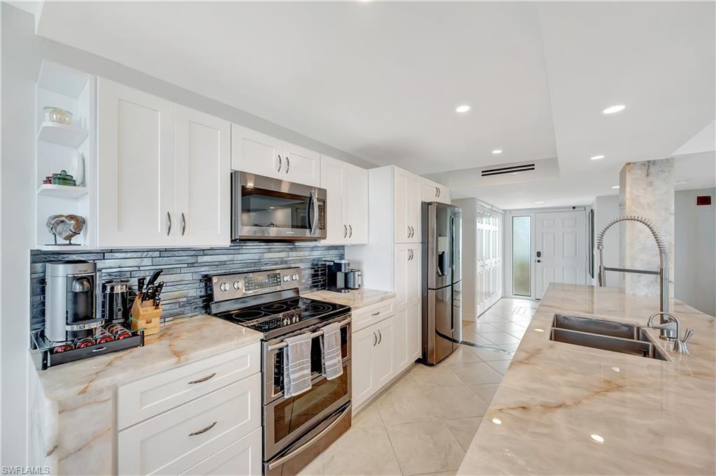 11 Bluebill Avenue, Unit 1101 Naples, FL 34108 - Photo 22 of 40 a kitchen with stainless steel appliances granite countertop a stove and a refrigerator