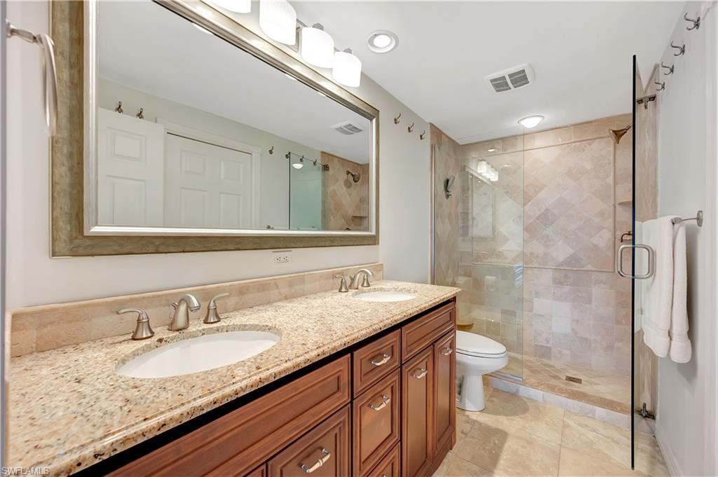 11 Bluebill Avenue, Unit 1101 Naples, FL 34108 - Photo 26 of 40 a bathroom with a granite countertop sink a toilet a mirror and shower