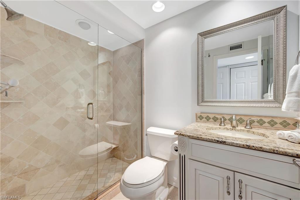 11 Bluebill Avenue, Unit 1101 Naples, FL 34108 - Photo 29 of 40 a bathroom with a granite countertop toilet a sink and a mirror