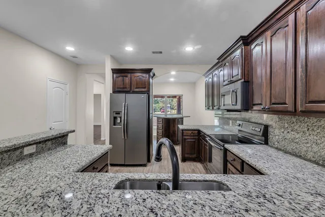 a view of a kitchen with stainless steel appliances granite countertop a sink refrigerator and microwave