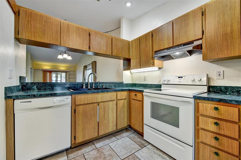 558 Capistrano Court Largo, FL 33771 - Photo 11 of 40 a kitchen with granite countertop wood cabinets and white appliances