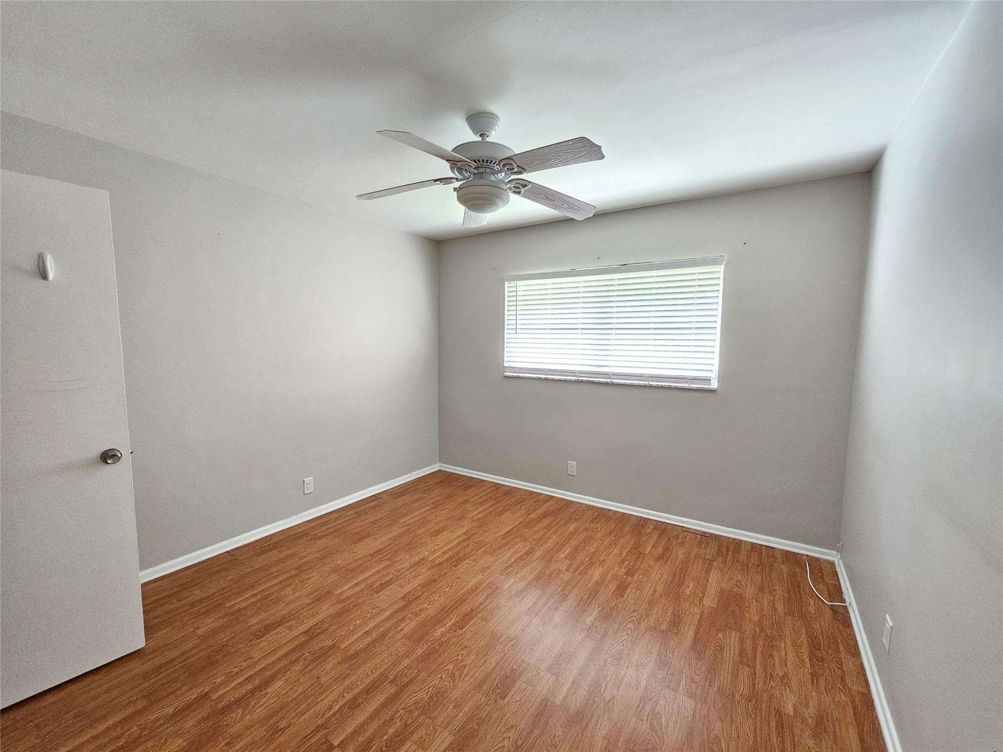 2120 Northeast 41st Street, Unit B Lighthouse Point, FL 33064 - Photo 6 of 24 an empty room with wooden floor fan and windows