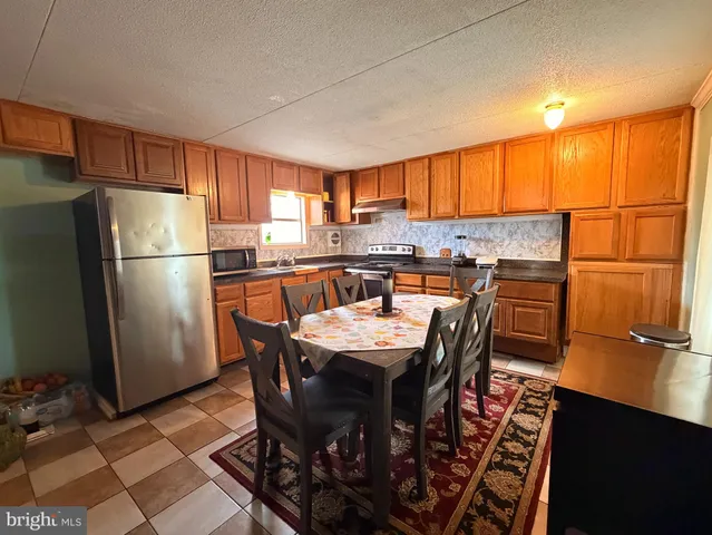 a kitchen with stainless steel appliances granite countertop a table chairs a refrigerator and a stove top oven