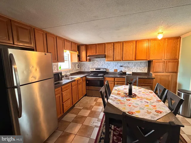 a kitchen with stainless steel appliances granite countertop a refrigerator a stove a sink dishwasher with a dining table and chairs