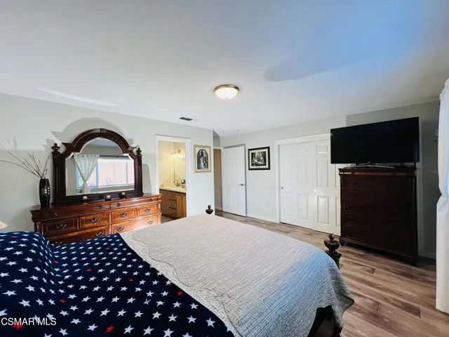 a bedroom with a bed and a dresser with wooden floor