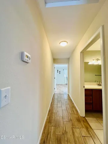 a view of a hallway with wooden floor and cabinet
