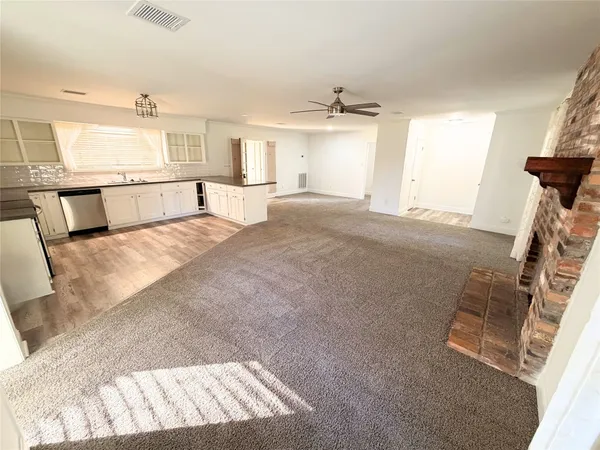 a kitchen with stainless steel appliances granite countertop a stove top oven a sink dishwasher a refrigerator and white cabinets with wooden floor