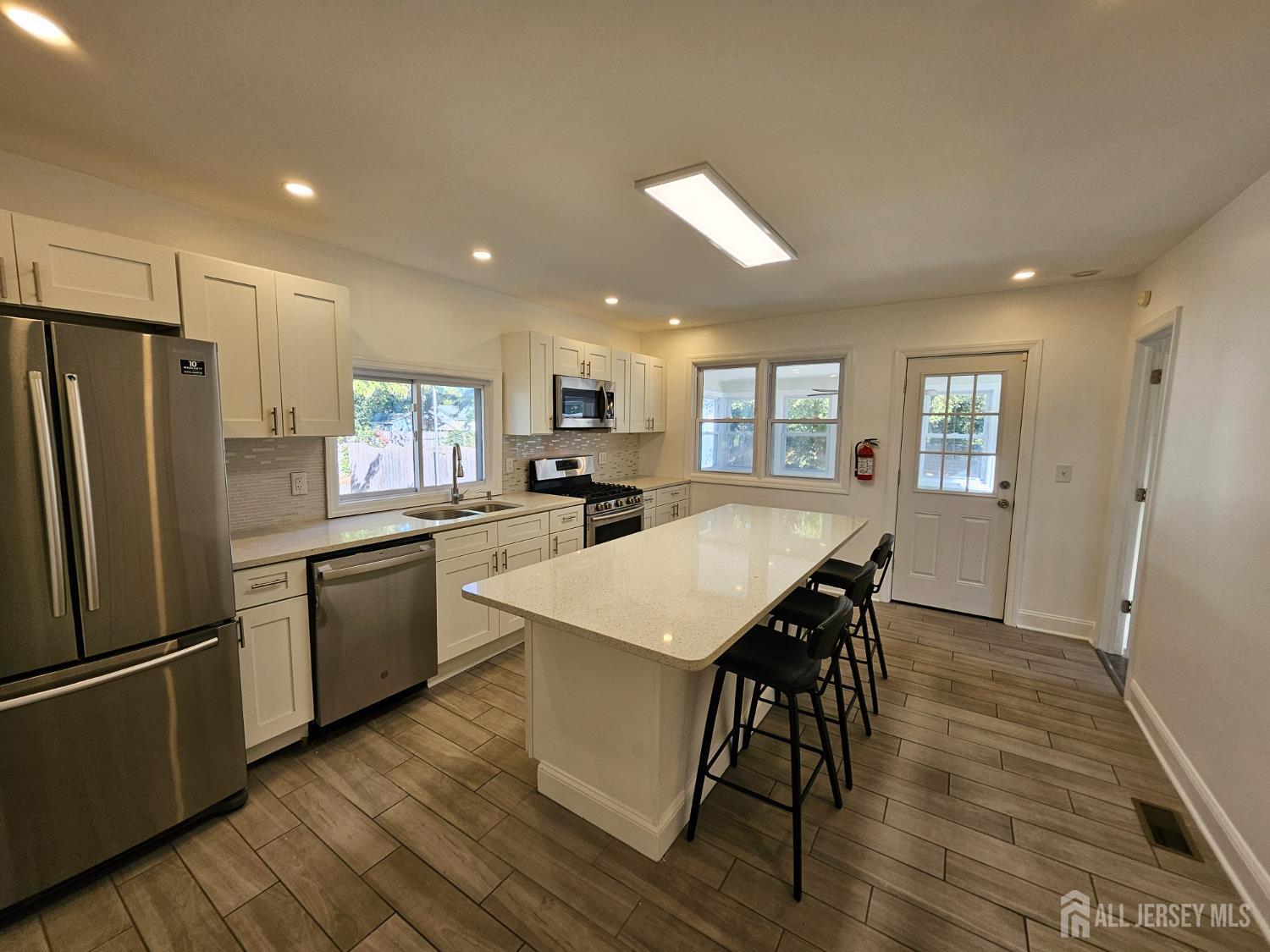 60 6th Avenue Trenton, NJ 08619 - Photo 15 of 28 a kitchen with stainless steel appliances kitchen island granite countertop a refrigerator a stove a sink dishwasher and a dining table with wooden floor