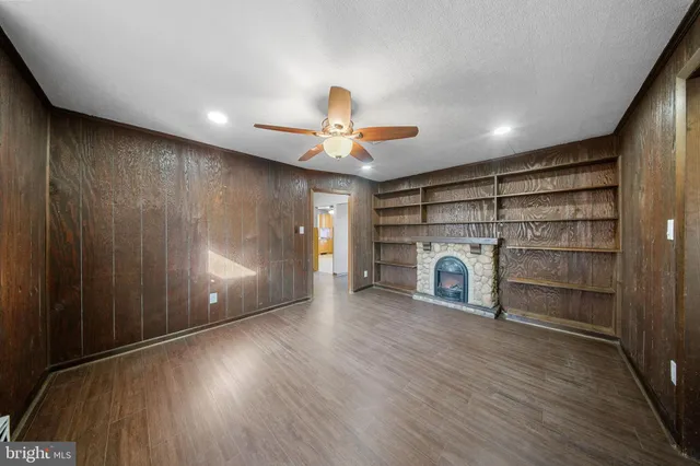 a view of a livingroom with a fireplace a ceiling fan and window