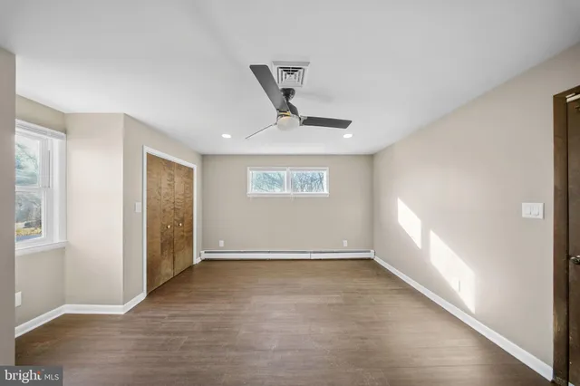 a view of an empty room with a window and wooden floor