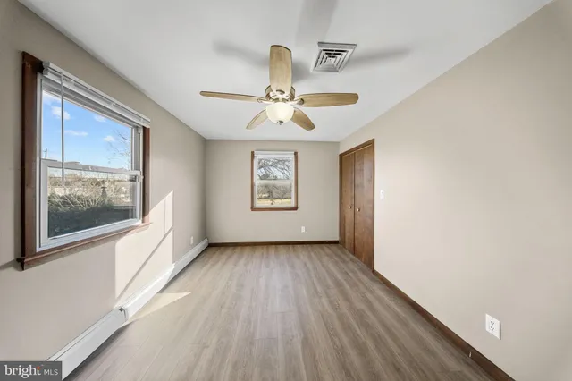 an empty room with wooden floor and a ceiling fan