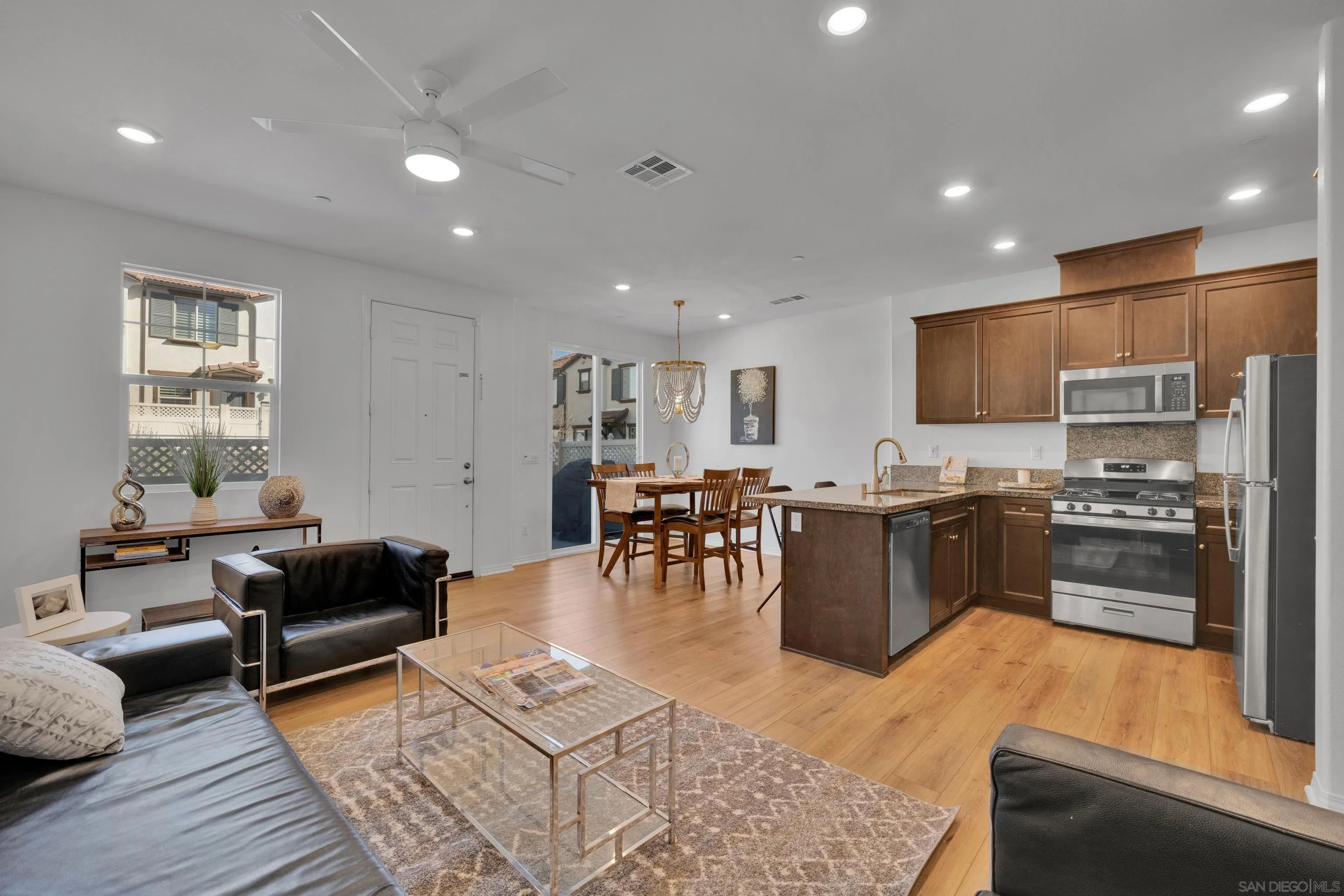 a living room with stainless steel appliances furniture and a kitchen view