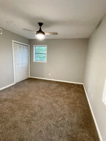an empty room with a ceiling fan and window