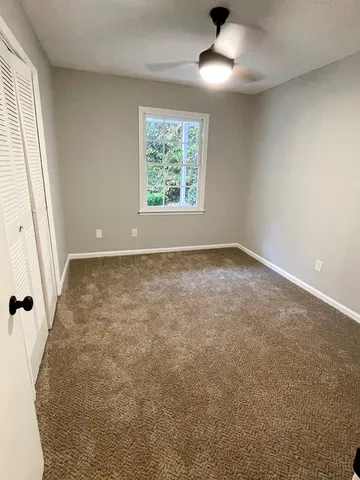 an empty room with windows and fan