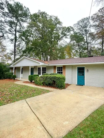 a front view of a house with a garden and trees