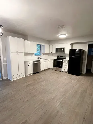 a large kitchen with a stove a refrigerator a sink dishwasher with a dining table and chairs