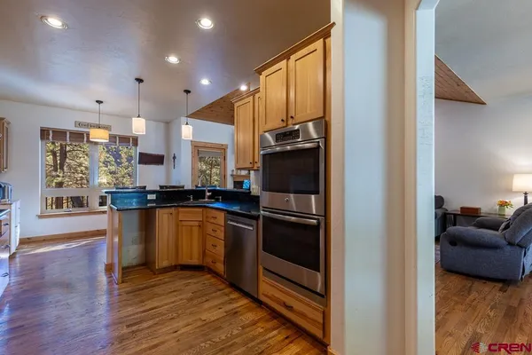 a living room with stainless steel appliances kitchen island granite countertop furniture a fireplace and a large window
